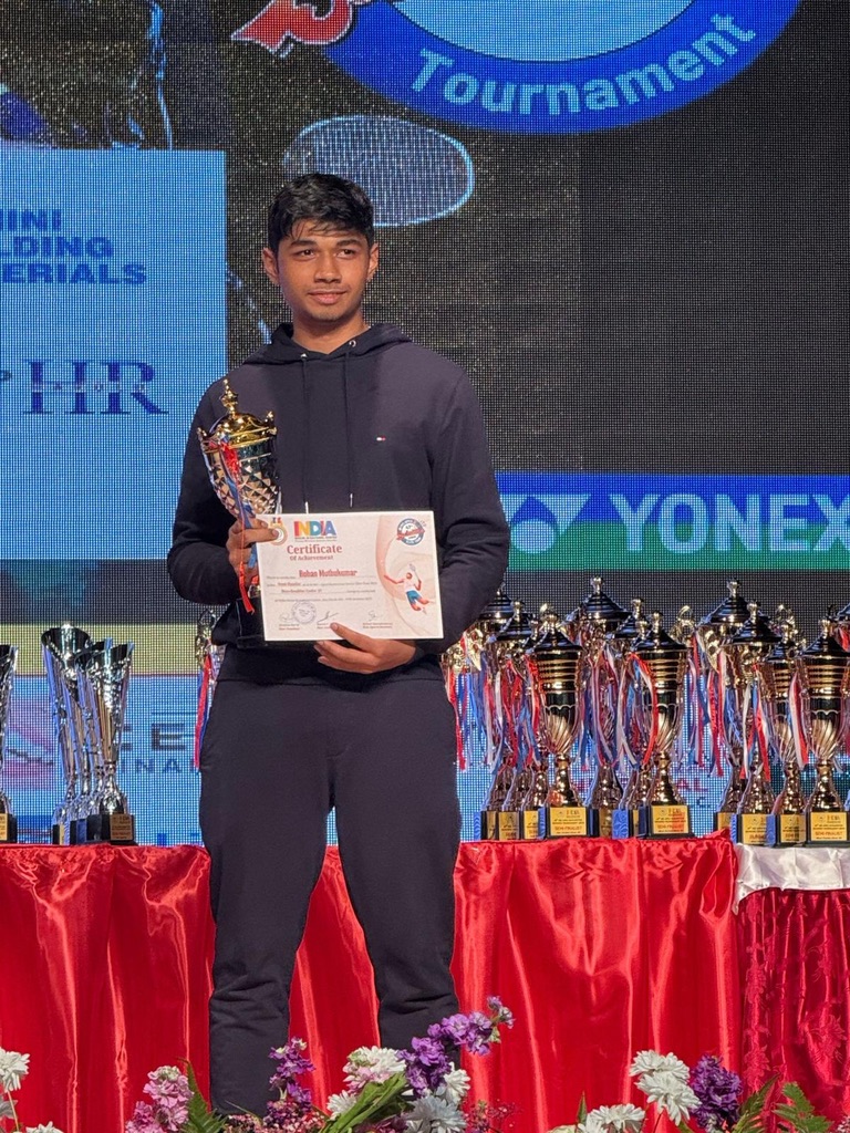 Rohan holding a trophy and certificate at a badminton tournament